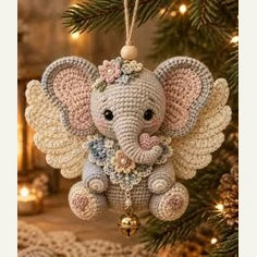 Éléphant décoratif aux oreilles ailées, suspendu à une branche de sapin