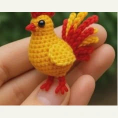 Coq miniature jaune et rouge posé au bout des doigts